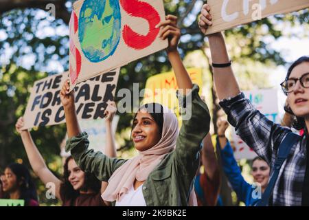 März des Klimawandels für Jugendliche. Gruppe multikultureller Jugendaktivisten, die Plakate und Banner tragen, während sie gegen die globale Erwärmung protestieren. Frohes junges p Stockfoto