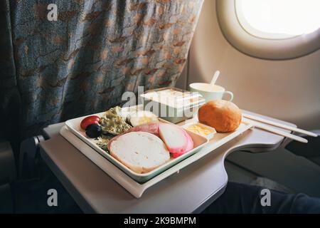 Mahlzeit per Flugzeug service Fach für Economy Class, Fleisch, Obst, Salat, Gurke, ein Glas Saft und Butter. Messer und Gabel aus Kunststoff für Sicherheit. Stockfoto