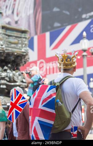 Am ersten Tag des Platinum Jubilee Weekends sieht ein Nachtschwärmer auf, wie eine Unionsflagge auf einer elektrischen Tafel im Piccadilly Circus, London, gezeigt wird. Stockfoto