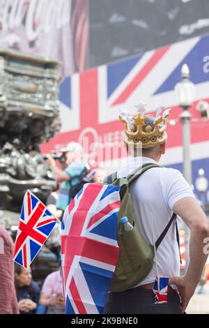 Am ersten Tag des Platinum Jubilee Weekends sieht ein Nachtschwärmer auf, wie eine Unionsflagge auf einer elektrischen Tafel im Piccadilly Circus, London, gezeigt wird. Stockfoto