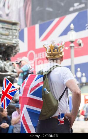 Am ersten Tag des Platinum Jubilee Weekends sieht ein Nachtschwärmer auf, wie eine Unionsflagge auf einer elektrischen Tafel im Piccadilly Circus, London, gezeigt wird. Stockfoto