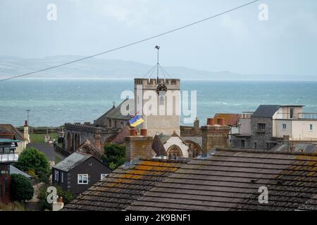 Blick auf die St. Michaels Kirche und das Meer bei Lyme Regis über die Dächer Stockfoto