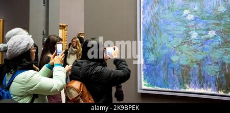 PARIS, FRANKREICH - 6. JANUAR 2019: Besucher bewundern und fotografieren Blauwasserlilien von Claude Monet im Musée d'Orsay, das für seinen großen Eindruck berühmt ist Stockfoto