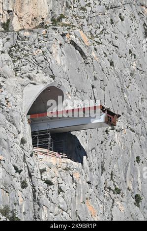 Das Projekt der Umgehungsstraße von Omis an der dalmatinischen Küste Kroatiens, das den Bau einer 216 Meter langen Brücke umfasst, die zwei Tunnel verbindet, ist in vollem Gange. Dies ist eines der komplexesten Infrastrukturprojekte, die derzeit in Kroatien durchgeführt werden, und wird auch den Bau der Schnellstraße Stobrec – Dugi Rat – Omis ermöglichen, die während der touristischen Saison dazu beitragen wird, Verkehrsprobleme auf der stark befahrenen Strecke Split-Omis zu lindern. Der Bau der Brücke 70 Meter über der Schlucht des Flusses Cetina, die den neuen Komorjak-Tunnel mit dem bestehenden Omis-Tunnel verbinden wird, begann im Jahr 2019. Konstruktio Stockfoto