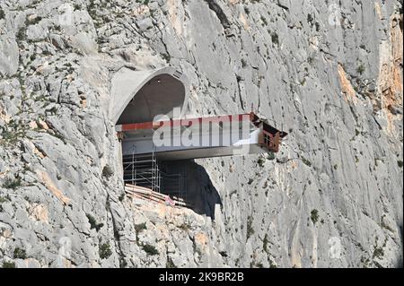 Das Projekt der Umgehungsstraße von Omis an der dalmatinischen Küste Kroatiens, das den Bau einer 216 Meter langen Brücke umfasst, die zwei Tunnel verbindet, ist in vollem Gange. Dies ist eines der komplexesten Infrastrukturprojekte, die derzeit in Kroatien durchgeführt werden, und wird auch den Bau der Schnellstraße Stobrec – Dugi Rat – Omis ermöglichen, die während der touristischen Saison dazu beitragen wird, Verkehrsprobleme auf der stark befahrenen Strecke Split-Omis zu lindern. Der Bau der Brücke 70 Meter über der Schlucht des Flusses Cetina, die den neuen Komorjak-Tunnel mit dem bestehenden Omis-Tunnel verbinden wird, begann im Jahr 2019. Konstruktio Stockfoto