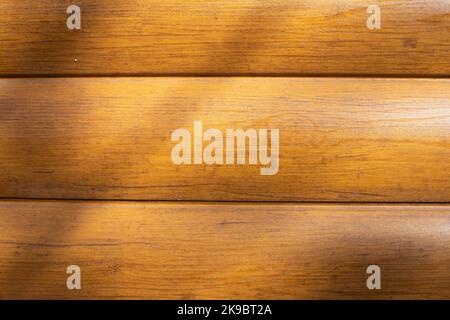 Schirm aus Holz. Holzhintergrund. Licht auf der Oberfläche. Braune Verkleidung aus Holz imitierender Plastik. Stockfoto