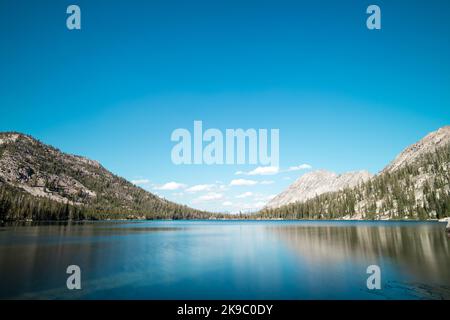 Toxaway Lake, in Idahos Sawtooth Wilderness an einem Sommertag gesehen, mit einem blauen Himmel, weißen Wolken, und eine Reflexion in den ruhigen Gewässern der Stockfoto