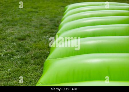 Aufblasbares Design. Trampolin zum Springen. Grünes Material. Air Three Designs. Kinderbereich. Die Hindernisstange ist im Detail. Stockfoto