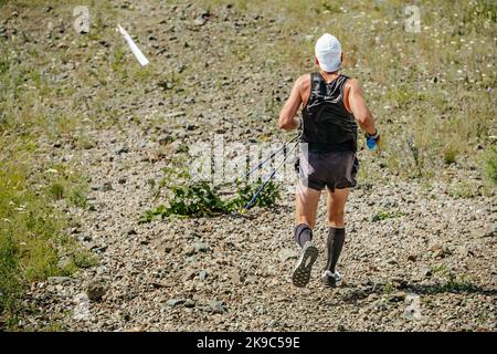 Rückenathlet mit Wanderstöcken beim Laufen Stockfoto