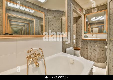 Weiße Badewanne mit Metallhahn im modernen Badezimmer und Toilette in minimalem Stil in der Wohnung Stockfoto