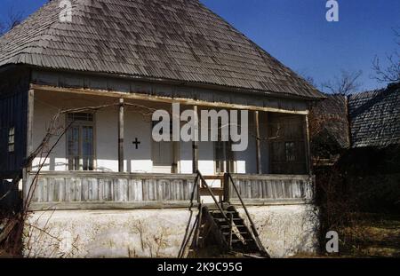 Traditionelles Haus mit Holzschindeldach in Gorj County, Rumänien, ca. 2000. Christliches Kreuz an der Fassade des Hauses, zum Schutz. Stockfoto