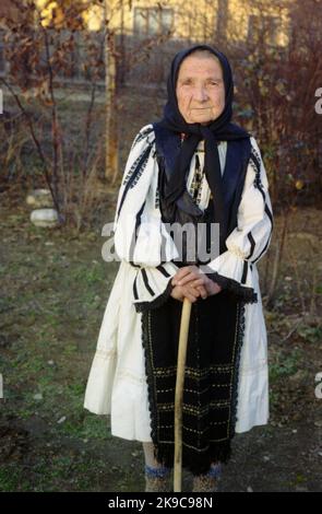 Kreis Gorj, Rumänien, ca. 2000. Ältere Frau mit Gehstock in schöner traditioneller einheimischer Kleidung. Stockfoto