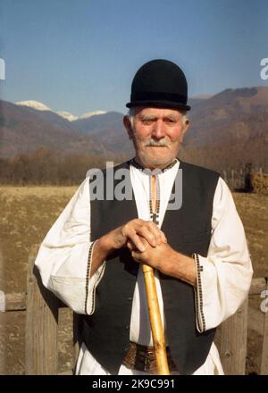 Kreis Gorj, Rumänien, ca. 2000. Älterer Mann mit Gehstock in traditioneller lokaler Kleidung. Stockfoto