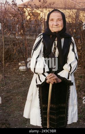 Kreis Gorj, Rumänien, ca. 2000. Ältere Frau mit Gehstock in schöner traditioneller einheimischer Kleidung. Stockfoto