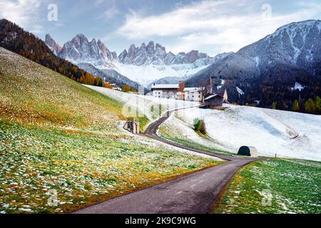 Das berühmte Bergdorf Santa Magdalena mit der Kirche Santa Maddalena in den herbstlichen Dolomiten. Verschneite Berggruppe der Geisler im Hintergrund. Val di Funes, Südtirol, Italien Stockfoto