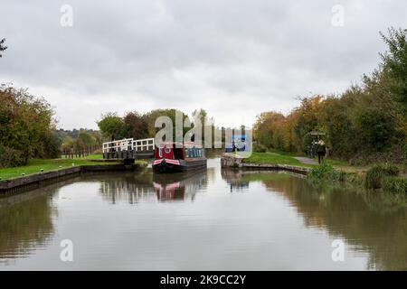 Ein farbenfrohes traditionelles schmales Boot, das durch die Milbrook-Drehbrücke am Kennet und Avon Canal, Wiltshire UK, fährt. Stockfoto