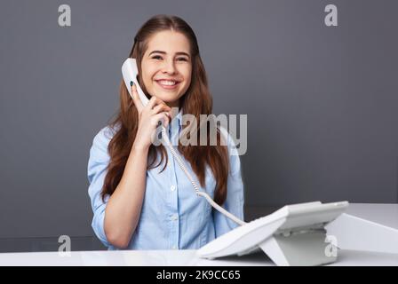 Der Rezeptionist war sehr nett und lächelte und sprach am Telefon. Stockfoto