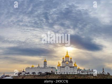 Magische Ansicht der Heiligen Dormition Pochajiv Lavra in der Ukraine. Panoramablick. Sonnenlicht über dem Kloster. Schwarze Wolken sammeln sich herum. Stockfoto