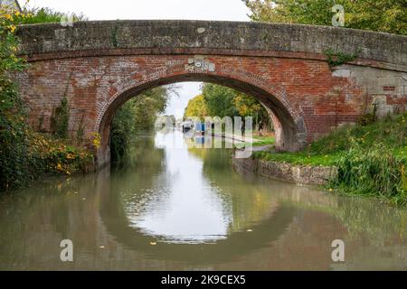 Verkauft die Grüne Brücke (Brücke 149) am Kennet und Avon Canal, Wiltshire, Großbritannien, mit traditionellen Schmalbooten in der Ferne. Stockfoto