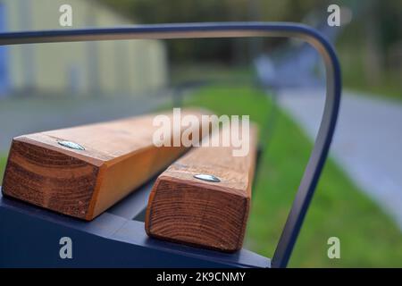 Eine braune Holzbank mit einem Metallgeländer vor einem verschwommenen Hintergrund in Polen Stockfoto