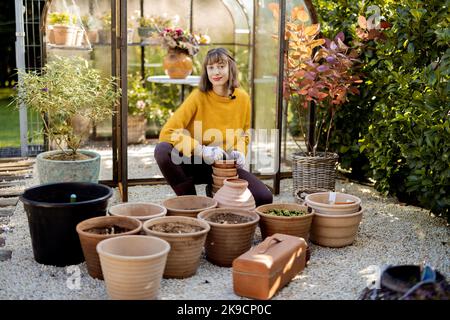 Frau pflanzt Blumen in Krügen im Garten Stockfoto