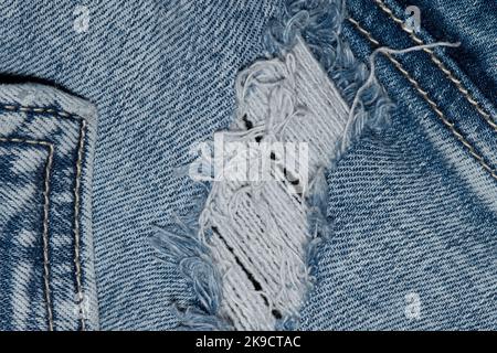 Zerrissene blaue Denim-Kleidung mit Taschennähten und Nähten. Flach lagen abgenutzte Jeans isoliert Abschnitt. Stockfoto