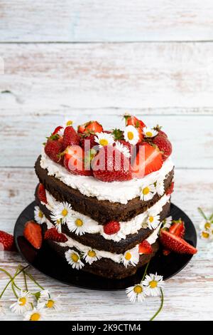 Schokoladen-Erdbeer-Herzkuchen mit Kamillenblumen-Dekoration Stockfoto