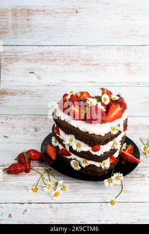 Schokoladen-Erdbeer-Herzkuchen mit Kamillenblumen-Dekoration Stockfoto