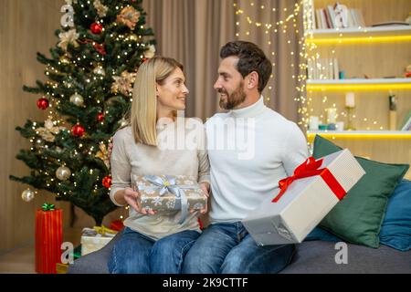 Ehepaar mittleren Alters tauscht Geschenke für weihnachten, Familie in der Liebe für weihnachten zu Hause sitzen auf dem Sofa zu Hause. Stockfoto