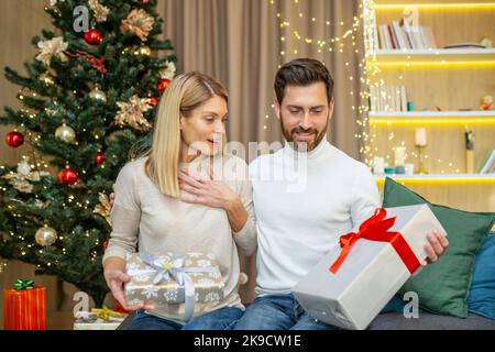 Ehepaar mittleren Alters tauscht Geschenke für weihnachten, Familie in der Liebe für weihnachten zu Hause sitzen auf dem Sofa zu Hause. Stockfoto