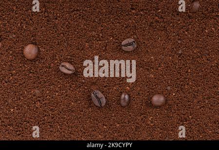 Voller Rahmen aus grob gemahlenem Kaffee und ein paar Kaffeebohnen darauf. Speicherplatz kopieren. Stockfoto