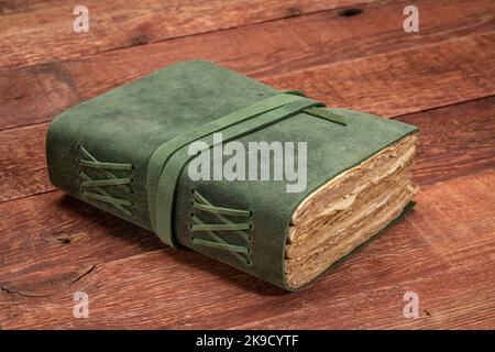 Retro-ledergebundene Zeitschrift mit dekorierter Kante handgefertigte Papierseiten auf einem rustikalen Scheunenholztisch, Journaling-Konzept Stockfoto