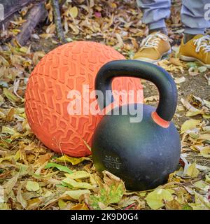 Schwere eiserne Kugelhantel und Slam Ball in einem Hinterhof, Herbstlandschaft Stockfoto