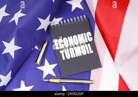 Geschäftskonzept. Auf der amerikanischen Flagge liegt ein Stift und ein Notizbuch mit der Aufschrift - wirtschaftliche Turbulenzen Stockfoto