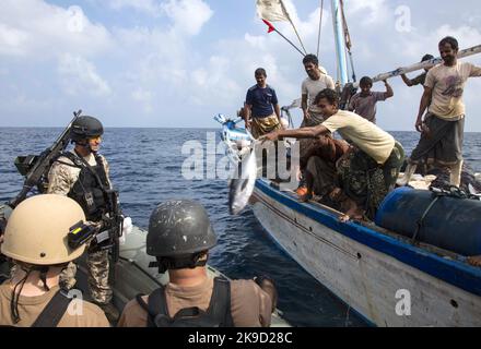 Jemenitischer Fischer gibt Seeleuten, die dem Visit, Board, Such- und Beschlagnahmungsteam (VBSS) des Lenkraketen-Zerstörers USS Mason (DDG 87) zugewiesen sind, einen Fisch. US-Marine Stockfoto