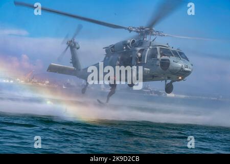 Ein US Naval Aircewman (Hubschrauber), der dem Chief of Naval Operations (CNO) Search and Rescue Model Manager (SARMM) der Helicopter Sea Combat Squadron (HSC) 3 zugewiesen wurde, springt während einer dynamischen Machbarkeitsstudie in Glorietta Bay in Coronado, Kalifornien, am 25. August 2022 vom MH-60s-Hubschrauber Sikorsky Seahawk. Stockfoto