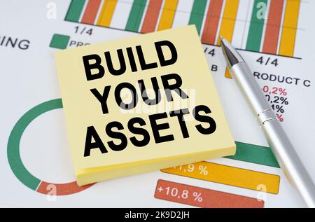 Geschäftskonzept. Auf den Geschäftskarten sind ein Stift und Aufkleber mit der Aufschrift - bauen Sie Ihre Vermögenswerte Stockfoto