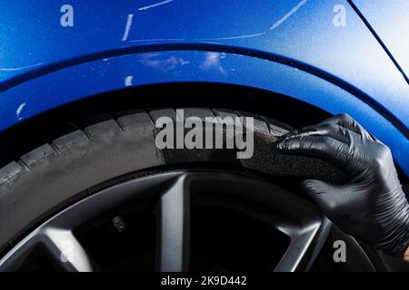 Schwärzung des Reifenrades des Autos mit Schwamm mit chemischer Schwärzung des Gummis in Detaillierung Auto-Service Stockfoto