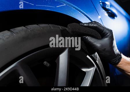 Schwärzung des Reifenrades des Autos mit Schwamm mit chemischer Schwärzung des Gummis in Detaillierung Auto-Service Stockfoto