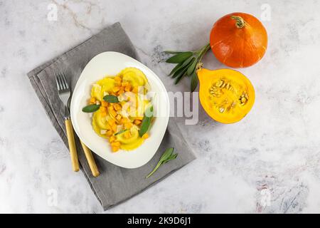 Saisonales Herbstrezept. Kürbisravioli mit Salbei, Parmesan und Olivenöl. Stockfoto