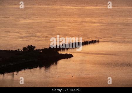 Einsamer Pier umgeben von Wasser während der goldenen Stunde . Stockfoto