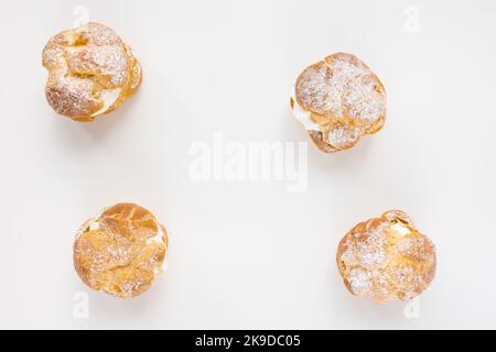 Choux Bun mit Schlagsahne und Zuckerpulver auf weißem Hintergrund. Zartes Dessert aus Choux-Gebäck. Französischer Cremetausch. Draufsicht, Kopierbereich Stockfoto