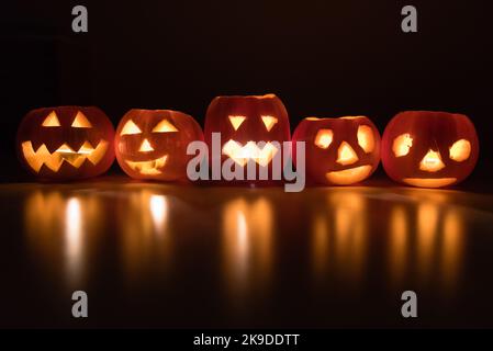 Olomouc, Tschechische Republik. 26. Oktober 2022. Halloween Kürbisse mit Kerzenlicht auf dem Tisch beleuchten einen dunklen Raum. Halloween wird am 31.. Oktober in vielen Ländern der Welt gefeiert. Zu den traditionellen Halloween-Aktivitäten gehören Trick or Treat, die Teilnahme an Halloween-Kostümpartys, Kürbisse schnitzen, gruselige Geschichten erzählen, Horror beobachten. (Bild: © Tomas Tkacik/SOPA Images via ZUMA Press Wire) Stockfoto