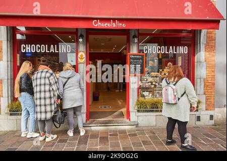 Brügge (Brügge) in Belgien und eine Gruppe von Touristen blicken in das Fenster eines der berühmten Chokloate-Geschäfte der Stadt Stockfoto