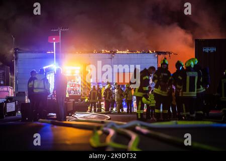 Bad Oeynhausen, Deutschland. 28. Oktober 2022. Die Feuerwehrleute stehen auf dem Gelände eines Abfallwirtschaftsunternehmens, in dem die Halle für gefährliche Abfälle in Brand steht. (To dpa 'gefährliche Abfallhalle in Bad Oeynhausen in Flammen') Quelle: Lino Mirgeler/dpa/Alamy Live News Stockfoto