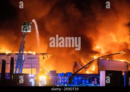 Bad Oeynhausen, Deutschland. 28. Oktober 2022. Ein Feuerwehrauto wird vor dem Grundstück eines Entsorgungsunternehmens geparkt, in dem die Halle für gefährliche Abfälle in Brand steht. Quelle: Lino Mirgeler/dpa/Alamy Live News Stockfoto