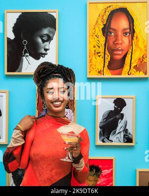 London, Großbritannien. 27. Oktober 2022. Fotografin Mahaneela posiert mit ihren Arbeiten, in Ocher, 2020 (oben rechts). Geladene Gäste und Künstler mischen sich und posieren mit den Bildern. Privatansicht der neuen Ausstellung 'The New Black Vanguard: Photography between Art and Fashion' in der Saatchi Gallery in London, unterstützt von Burberry. Die Ausstellung zeigt 15 internationale Black-Fotografen und ist eine Hommage an die Kreativität der Schwarzen vor und hinter der Kamera, die bis zum 22. Januar 2023 läuft. Kredit: Imageplotter/Alamy Live Nachrichten Stockfoto