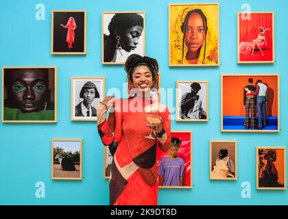 London, Großbritannien. 27. Oktober 2022. Fotografin Mahaneela posiert mit ihren Arbeiten, in Ocher, 2020 (drittes Bild, obere Reihe). Geladene Gäste und Künstler mischen sich und posieren mit den Bildern. Privatansicht der neuen Ausstellung 'The New Black Vanguard: Photography between Art and Fashion' in der Saatchi Gallery in London, unterstützt von Burberry. Die Ausstellung zeigt 15 internationale Black-Fotografen und ist eine Hommage an die Kreativität der Schwarzen vor und hinter der Kamera, die bis zum 22. Januar 2023 läuft. Kredit: Imageplotter/Alamy Live Nachrichten Stockfoto