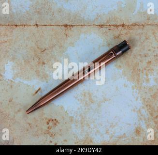 Vintage-Schreibstift auf verblichenem Papiertextur-Hintergrund in der Nahaufnahme Stockfoto