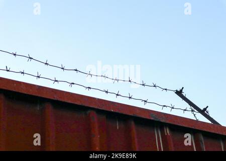 Ein Eisenzaun mit Stacheldraht auf der Oberseite. Sicherheitseinrichtung Stockfoto